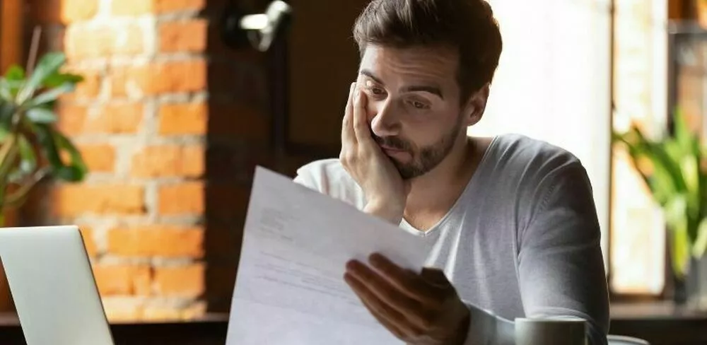 En mann sitter og lener seg på håneden sin mens har ser på et ark. Foto